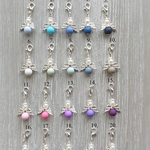 May include: Twenty silver angel charms with different colored beads. The charms are numbered 1 through 20.