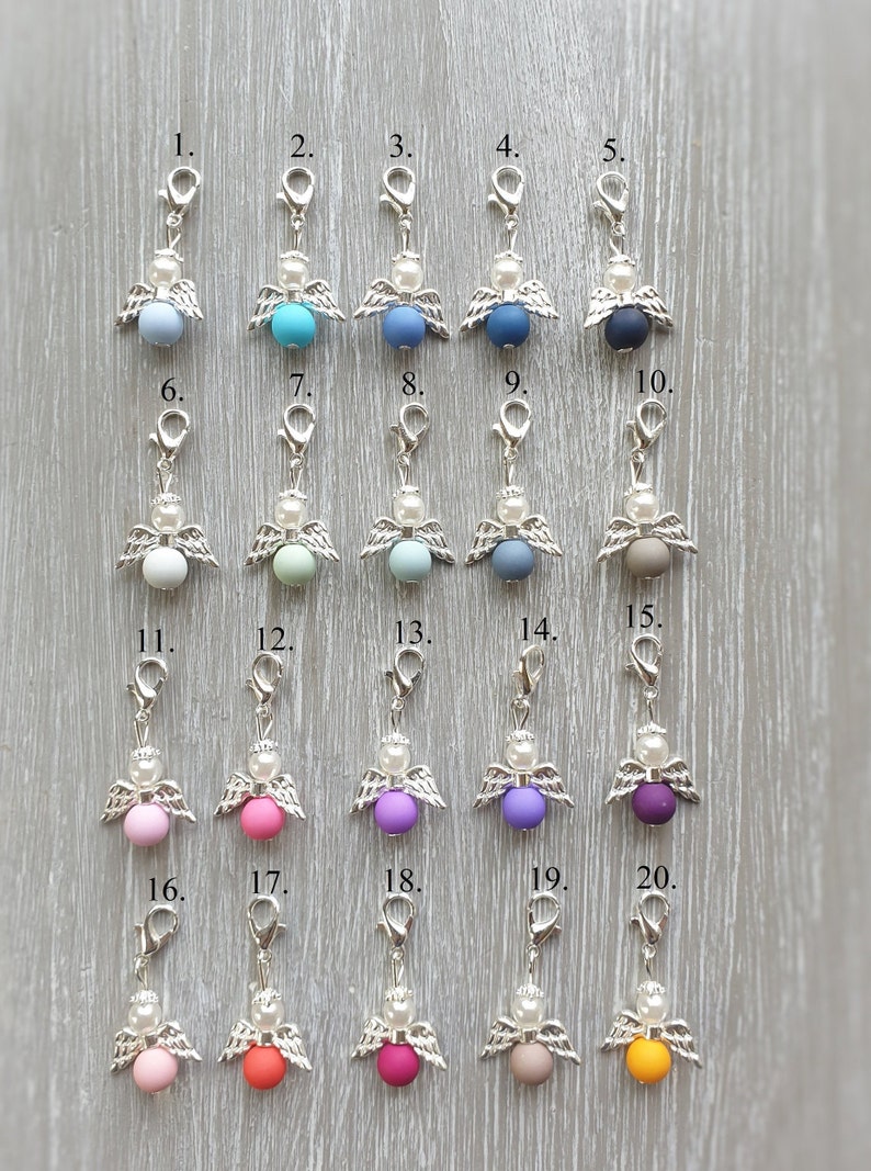 May include: Twenty silver angel charms with different colored beads. The charms are numbered 1 through 20.