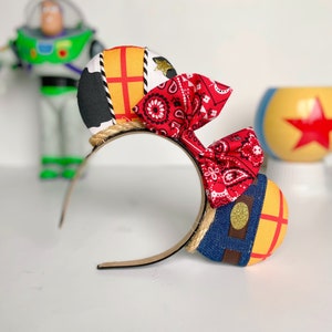 Peut inclure: Une paire d'oreilles de Minnie Mouse faites &agrave; la main sur le th&egrave;me de Disney avec un bandana rouge, un motif en tissu denim et jaune et un bandeau en corde marron.