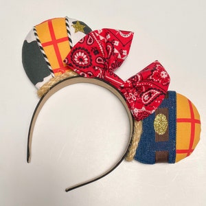 Peut inclure: Une paire d'oreilles de Minnie Mouse faites &agrave; la main avec un n&oelig;ud bandana rouge, un motif en tissu denim et jaune et un bandeau en corde marron.