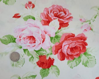 May include: Floral fabric featuring large, vibrant roses in shades of red and pink, with green leaves. The roses are clustered together on a cream-colored background, creating a classic, romantic pattern. The fabric is likely used for quilting or home decor.