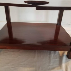 May include: A dark brown wooden table with a shelf. The table has a unique design with a cutout in the top surface.