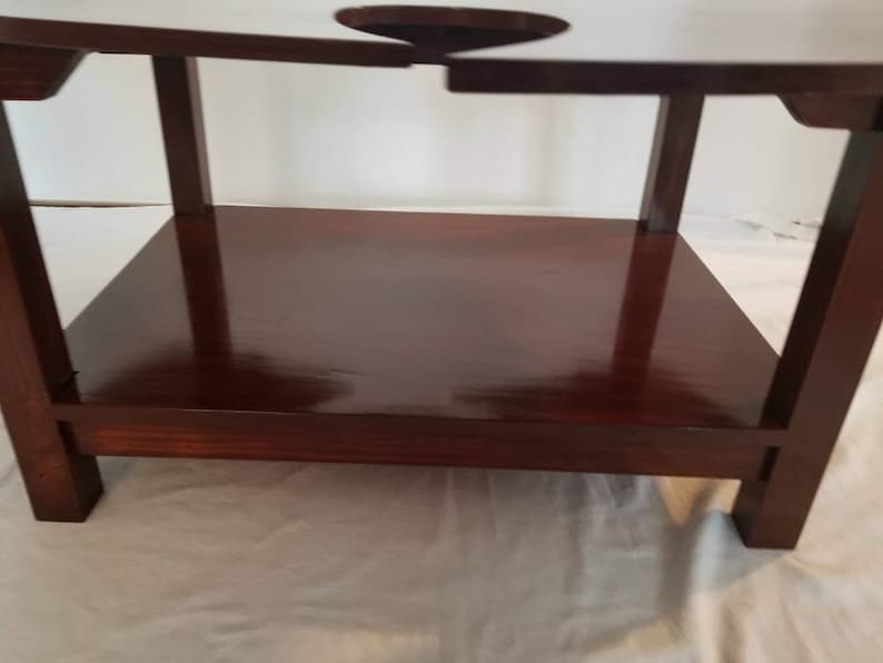 May include: A dark brown wooden table with a shelf. The table has a unique design with a cutout in the top surface.