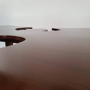 May include: A dark brown wooden table with two cut-out circles in the surface.