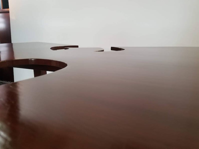 May include: A dark brown wooden table with two cut-out circles in the surface.