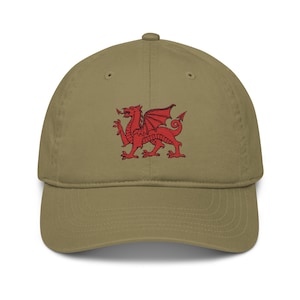 May include: A khaki baseball cap with a red embroidered Welsh dragon on the front.