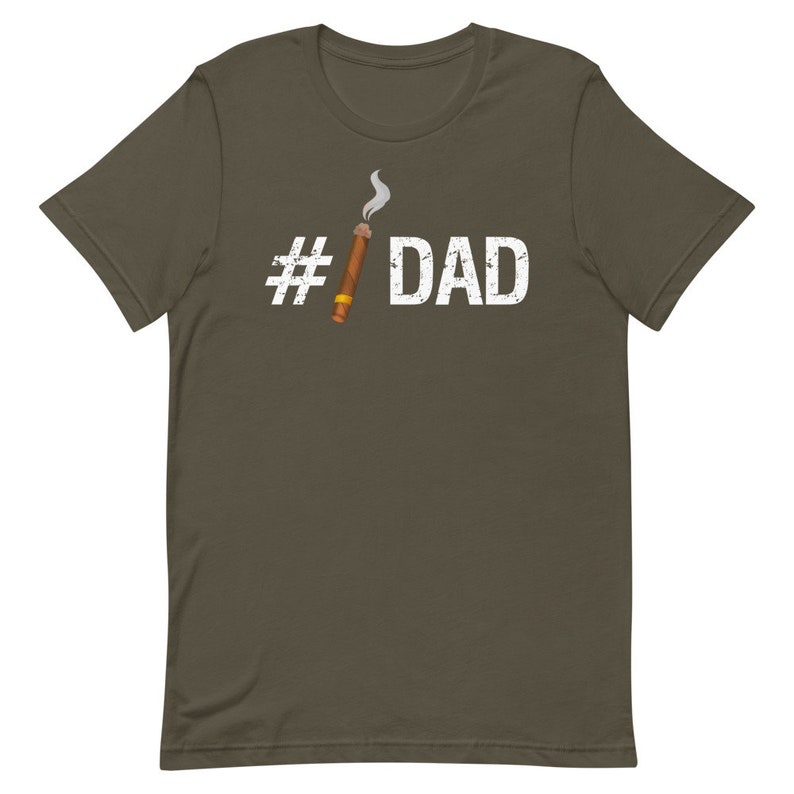 Puede incluir: Una camiseta verde oscuro con un hashtag blanco y la palabra "DAD" impresa en ella. Un cigarro de dibujos animados con humo est&aacute; al lado del hashtag.