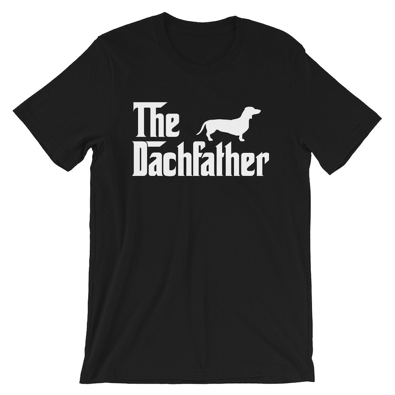 May include: Black t-shirt with the text "The Dachfather" in white, featuring a silhouette of a dachshund dog. The design is a parody of the movie "The Godfather".