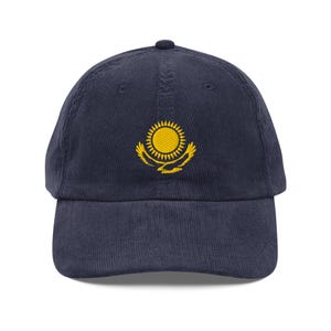 May include: A navy blue corduroy baseball cap with an embroidered yellow emblem of the flag of Kazakhstan.