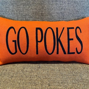 K&ouml;nnte beinhalten: Orangefarbener Lendenkissen mit schwarzem Text "GO POKES".