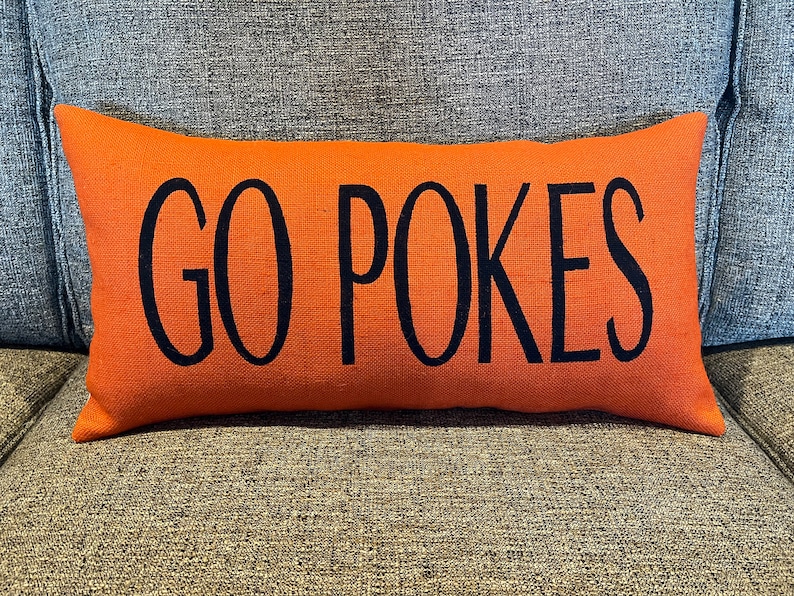 K&ouml;nnte beinhalten: Orangefarbener Lendenkissen mit schwarzem Text "GO POKES".