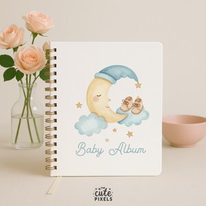 May include: A spiral-bound baby album with a cream-colored cover. The cover features a watercolor illustration of a smiling crescent moon wearing a blue nightcap, with baby shoes on a cloud. The words "Baby Album" are written in light blue.