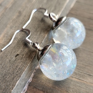 May include: A pair of silver dangle earrings with clear glass orbs filled with iridescent glitter.