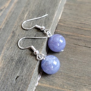 May include: A pair of silver earrings with light blue round gemstone beads.