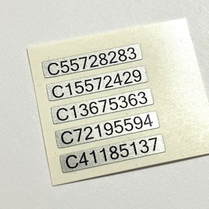 May include: A sheet of silver stickers with five black numbers on each sticker. The numbers are: C55728283, C15572429, C13675363, C72195594, and C41185137.
