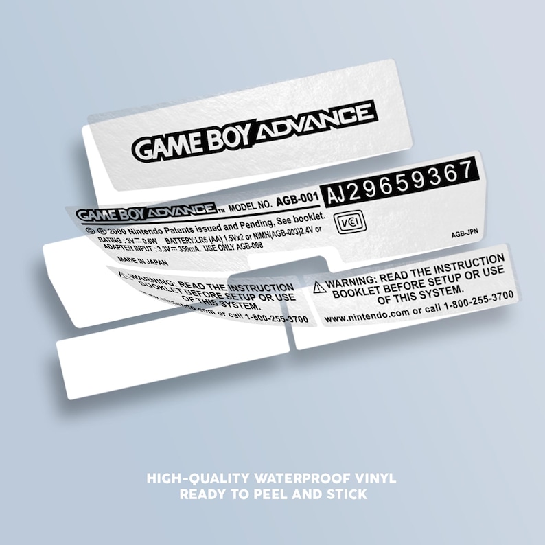 May include: A white sticker with black text for a Game Boy Advance console. The sticker has the text "GAME BOY ADVANCE" and "MODEL NO. AGB-001" and a serial number "AJ29659367". The sticker also has a warning to read the instruction booklet before setup or use of the system.