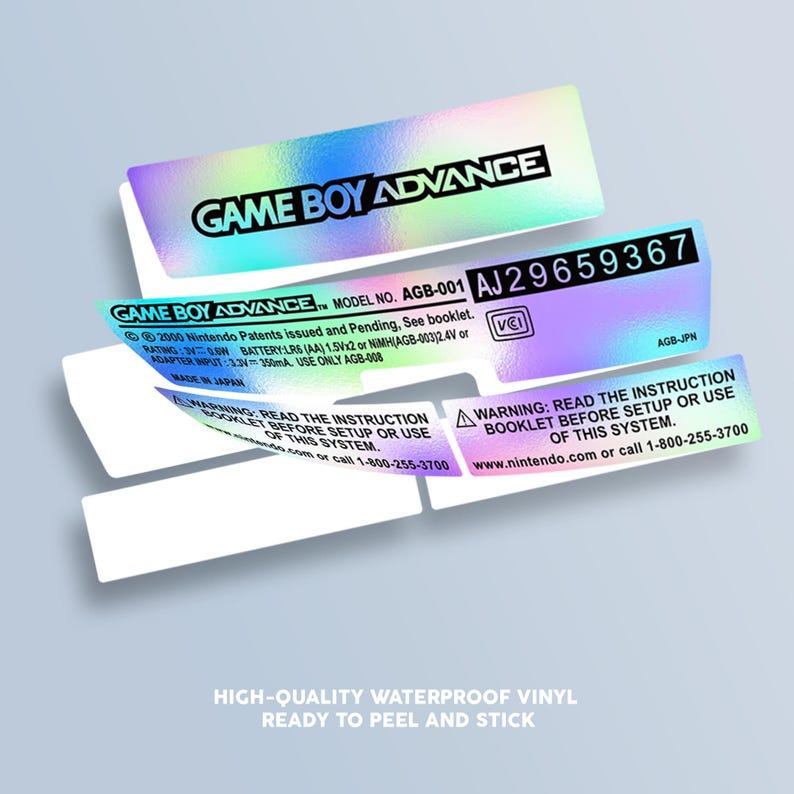 May include: A holographic sticker for a Game Boy Advance console. The sticker is iridescent and features the text "GAME BOY ADVANCE" in black letters. The sticker also includes the model number "AGB-001" and a serial number "AJ29659367".