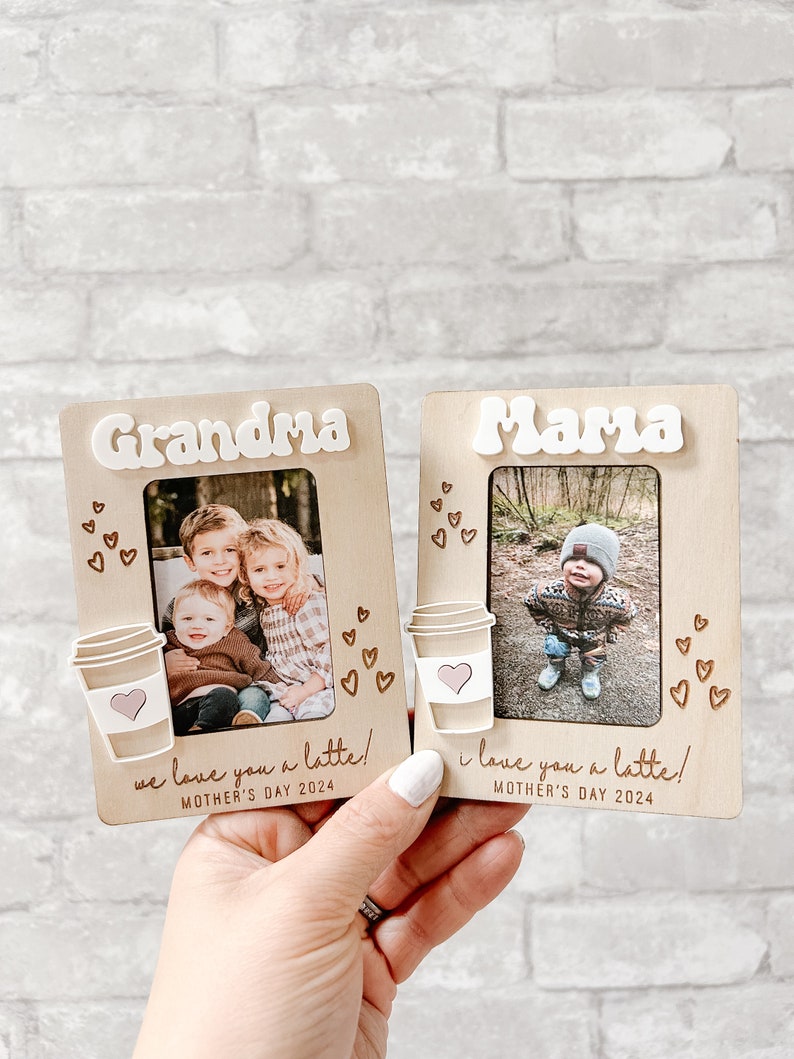 Puede incluir: Dos marcos de fotos de madera con un dise&ntilde;o de taza de caf&eacute; y las palabras "Grandma" y "Mama" en ellos. Cada marco tiene una foto de ni&ntilde;os y el texto "we love you a latte!" y "i love you a latte!" con la fecha "Mother's Day 2024" debajo.