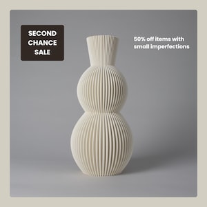 Könnte beinhalten: Eine cremefarbene Vase mit gerippter, vertikaler Textur und einer gestapelten, dreiteiligen kugelförmigen Silhouette. Das Bild enthält den Text "SECOND CHANCE SALE" in einem dunklen Feld und "50% off items with small imperfections" in weiß.