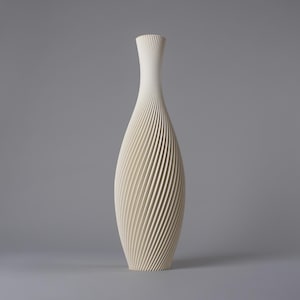 Puede incluir: Un jarrón alto de color crema con un cuello delgado y un cuerpo ancho y redondeado. El jarrón presenta un diseño en espiral de líneas verticales que crean una superficie texturizada. El jarrón mide unos 30 cm de alto.