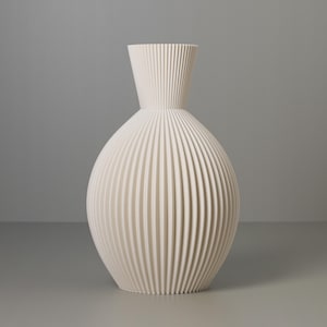 May include: A white ceramic vase with a ribbed design. The vase has a round body and a narrow neck.
