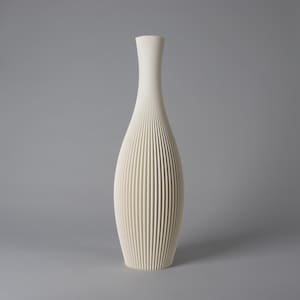 Könnte beinhalten: Eine hohe, cremeweiße Vase mit schlankem Hals und bauchigem Körper, die eine durchgehende vertikale Rippenstruktur aufweist, welche von der schmalen Öffnung bis zum flachen Boden verläuft und ein gleichmäßiges Muster auf der Oberfläche bildet.