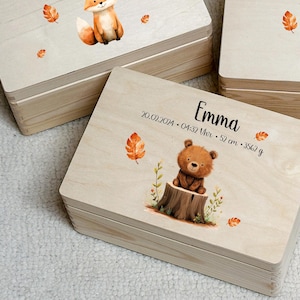 Pode incluir: Três caixas de madeira com tampas, cada uma decorada com um animal diferente e personalizada com um nome, data, hora e peso. As caixas estão empilhadas uma em cima da outra. Os animais são uma raposa, um ouriço e um urso.