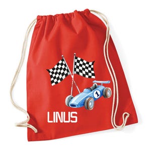 Könnte beinhalten: Roter Turnbeutel mit blauem Rennwagen, Nummer 1 und zwei karierten Flaggen. Der Name "LINUS" ist weiß aufgedruckt. Die Tasche hat einen Kordelzugverschluss und ist aus weichem Material.