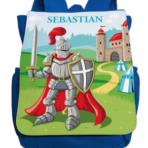 Può includere: Zaino blu con il nome personalizzato "SEBASTIAN" sul davanti. La tasca anteriore presenta un'illustrazione di un cavaliere in armatura che tiene una spada e uno scudo, in piedi davanti a un castello con tetto rosso e un campo verde.