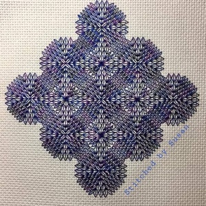 Op de afbeelding: Een close-up van een blauw en paars borduurwerk op witte stof. Het ontwerp heeft een herhalend patroon van geometrische vormen en sterren. De tekst "Stitched by Susan" is zichtbaar in de rechterbenedenhoek.