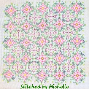 Puede incluir: Patrón de punto de cruz con un diseño floral repetitivo en rosa, amarillo, verde y azul sobre un fondo blanco. El texto "Stitched by Michelle" está en la parte inferior en verde.