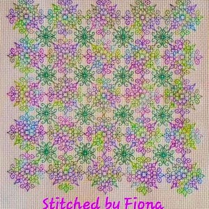 Könnte beinhalten: Ein Kreuzstichmuster mit einem sich wiederholenden Muster aus bunten Blumen und Wirbeln. Der Hintergrund ist hellbeige. Der Text "Stitched by Fiona" befindet sich am unteren Rand des Bildes.