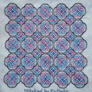 Puede incluir: Un patrón de punto de cruz con un diseño geométrico repetitivo de flores rosas, azules y negras. El patrón está cosido en tela blanca y tiene un borde negro. El texto "Stitched by Katinka" está en la parte inferior de la imagen.
