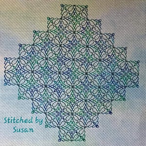 May include: A blue and green geometric cross-stitch pattern on a white background. The pattern is stitched in a diamond shape and has a repeating design. The text "Stitched by Susan" is in the bottom left corner of the image.