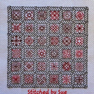 Könnte beinhalten: Ein schwarzer und roter Kreuzstich-Sampler mit verschiedenen Designs. Der Sampler ist mit einem schwarzen Rahmen versehen und der Text "Stitched by Sue" befindet sich unten.