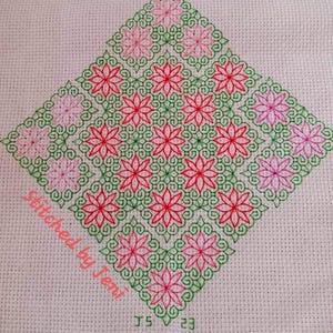 May include: A cross-stitch pattern with pink and red flowers on a white background. The flowers are outlined in green. The text "Stitched by Jen" is in the bottom left corner.