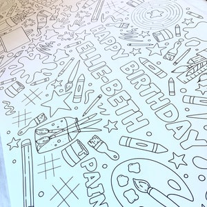 May include: A black and white coloring page with a birthday theme. The page features the words "Happy Birthday Ellie" and various art supplies, including paintbrushes, paint, pencils, and crayons.