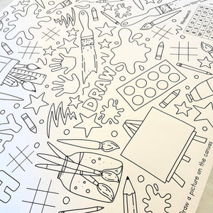 May include: A black and white coloring page featuring a variety of art supplies, including paintbrushes, paint palettes, pencils, and a canvas. The page also includes the word "DRAW" written in large letters. The text "Draw a picture on the canvas" is at the bottom of the page.