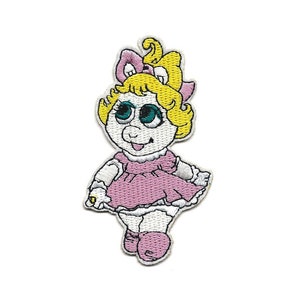 May include: Embroidered patch featuring a cartoon piglet with blonde hair, wearing a pink dress and white shoes. The piglet has large blue eyes and a pink bow in her hair.