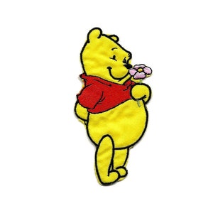 Peut inclure: Patch brodé jaune représentant Winnie l'ourson, un personnage de dessin animé, avec une chemise rouge et une fleur rose.