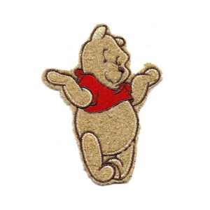 May include: A brown and beige embroidered Winnie the Pooh patch with a red shirt. The patch is perfect for adding a touch of Disney magic to your projects.