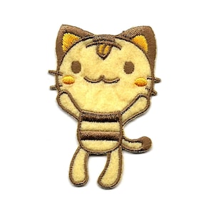 May include: A yellow and brown embroidered iron-on patch of a cartoon cat with a striped shirt. The cat is smiling and has its arms raised.