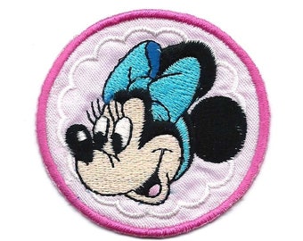 Könnte beinhalten: Ein gestickter Aufnäher mit einem Cartoon-Bild von Minnie Mouse mit einer blauen Schleife in Rosa und Weiß.