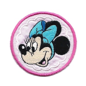 May include: An embroidered patch featuring a cartoon image of Minnie Mouse with a blue bow, in pink and white.