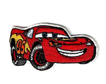 May include: Red cartoon racing car with a smiling face and the number 95 on the side. The car is embroidered on a white background.