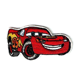May include: Red cartoon race car with a smiling face and the number 95 on the side. The car is embroidered on a white background.