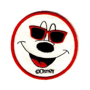 May include: Embroidered patch of a smiling cartoon face wearing sunglasses. The face is white with a black nose and mouth, and red sunglasses. The patch has a red border and the Disney logo.