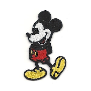 May include: Black and white embroidered cartoon image of Mickey Mouse wearing red shorts and yellow shoes.