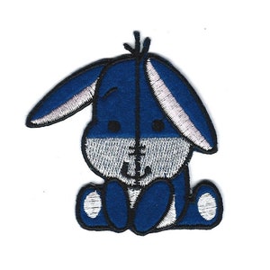May include: A blue and white embroidered iron-on patch featuring a cartoon donkey with a big smile.