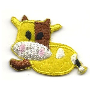 May include: A yellow and brown embroidered iron-on patch of a cartoon cow with white spots and pink nose.